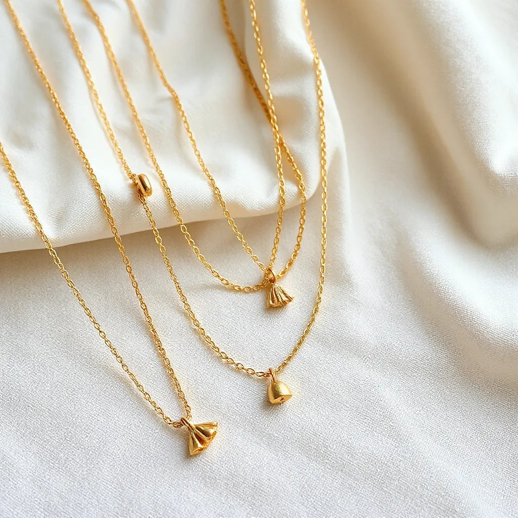Layered dainty gold necklaces with small pendants resting on neutral fabric under soft light