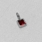 red birthstone pendant in silver on a white background