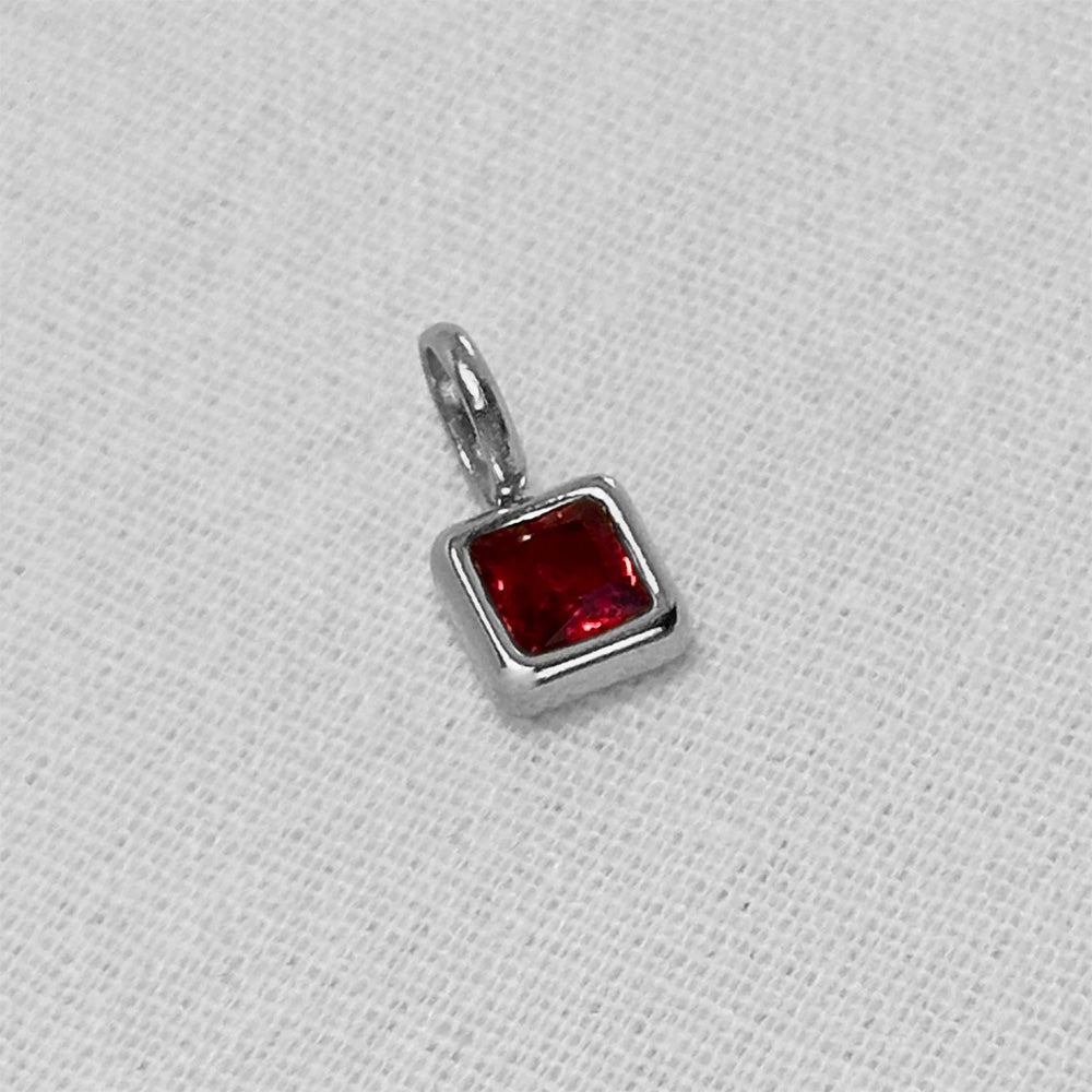 red birthstone pendant in silver on a white background