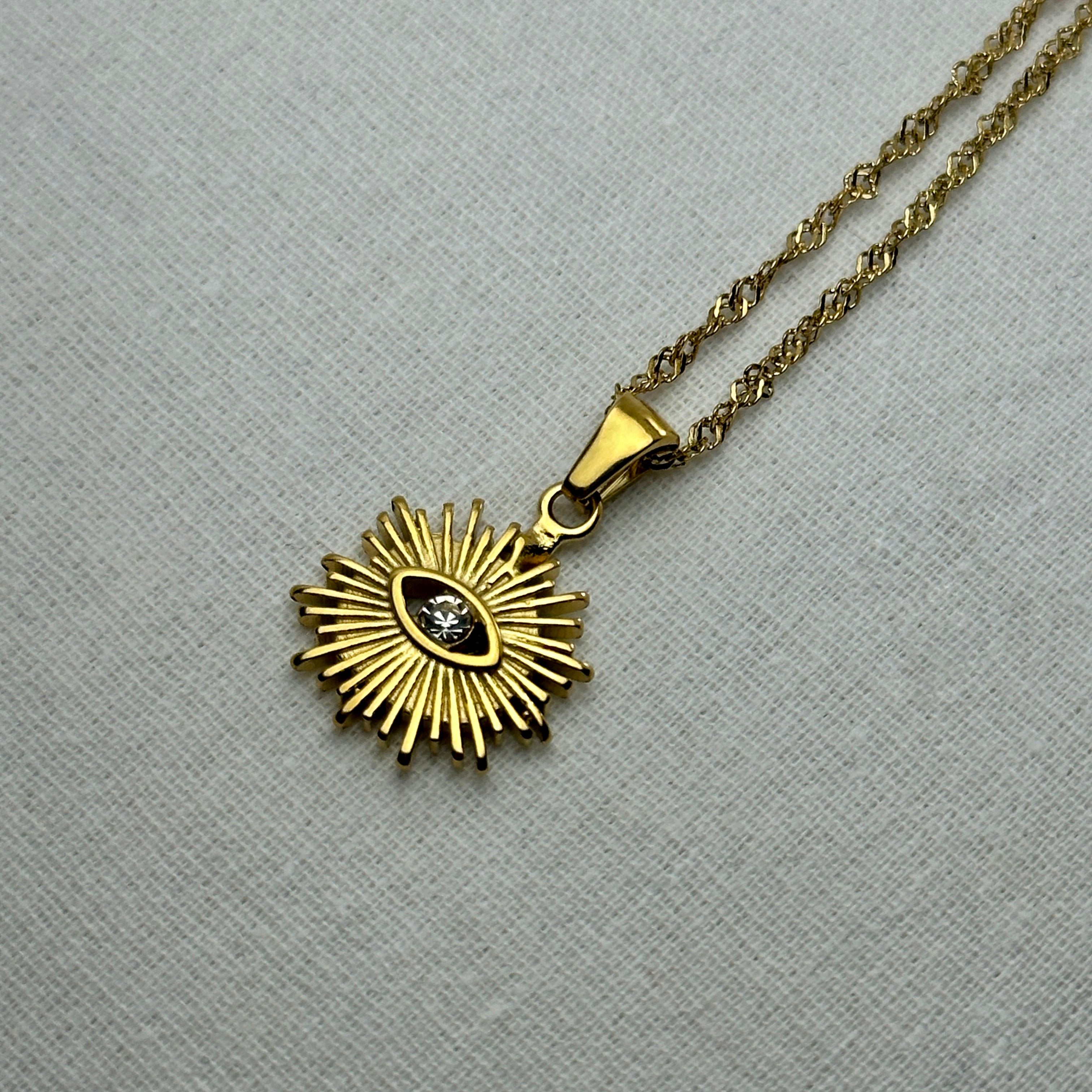 Gold chain necklace with an eye-shaped pendant.
