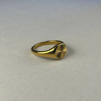 Gold signet ring with engraved sunburst pattern on white fabric background