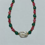 Necklace with green, pink, and gold beads on a white background
