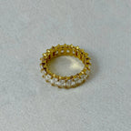 gold eternity ring with square clear stones on white fabric background
