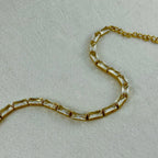 Gold chain bracelet with rectangular clear crystals on textured light fabric background