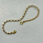 gold bracelet with rectangular clear stones and a delicate chain on white fabric background