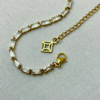 Elegant gold chain necklace with rectangular clear crystals and lobster clasp on white fabric