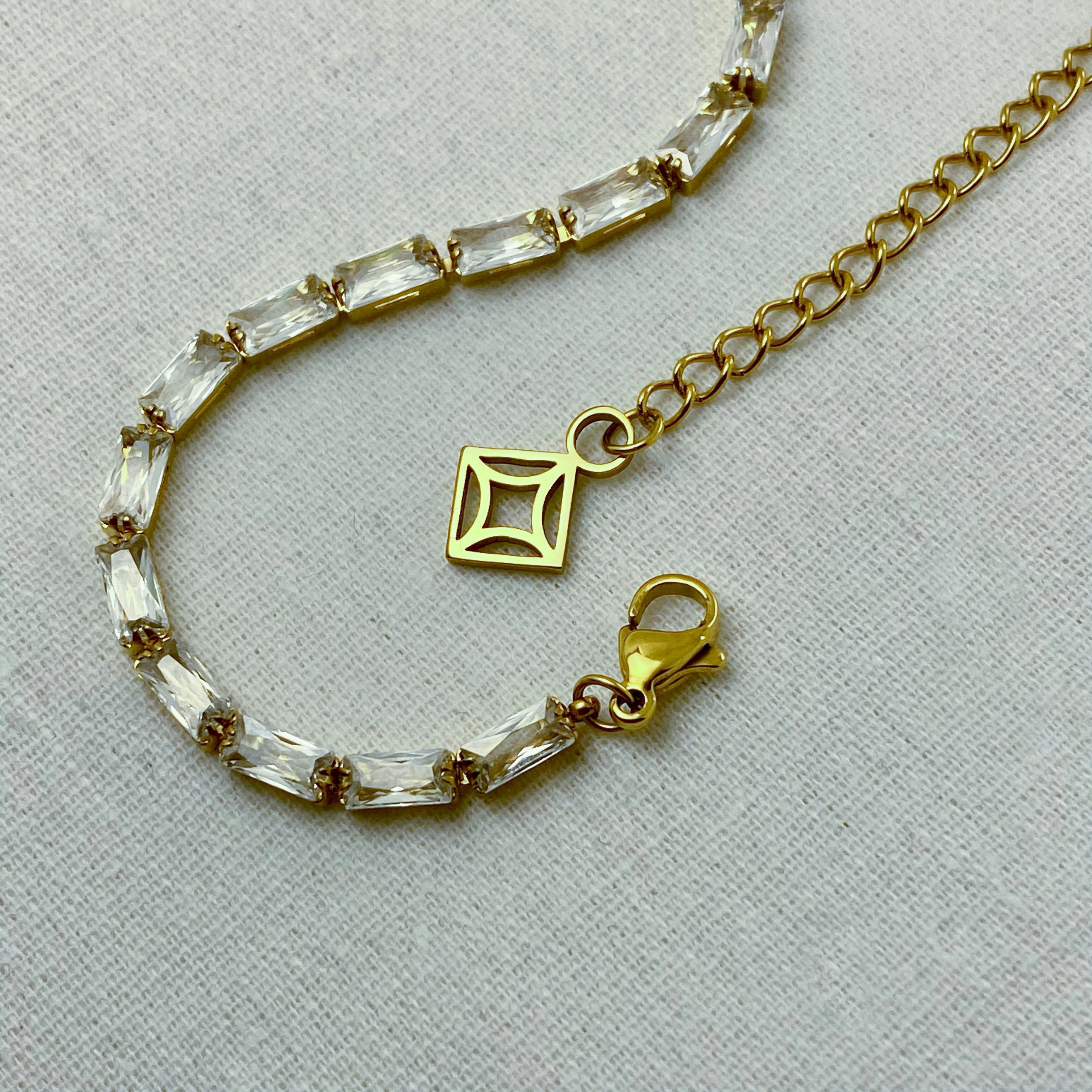 Close-up of a gold bracelet with clear, rectangular stones.