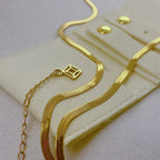 Gold snake chain necklace with adjustable clasp on beige jewelry pouch