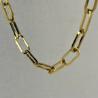 Close-up of a gold rectangular link chain necklace on a neutral background