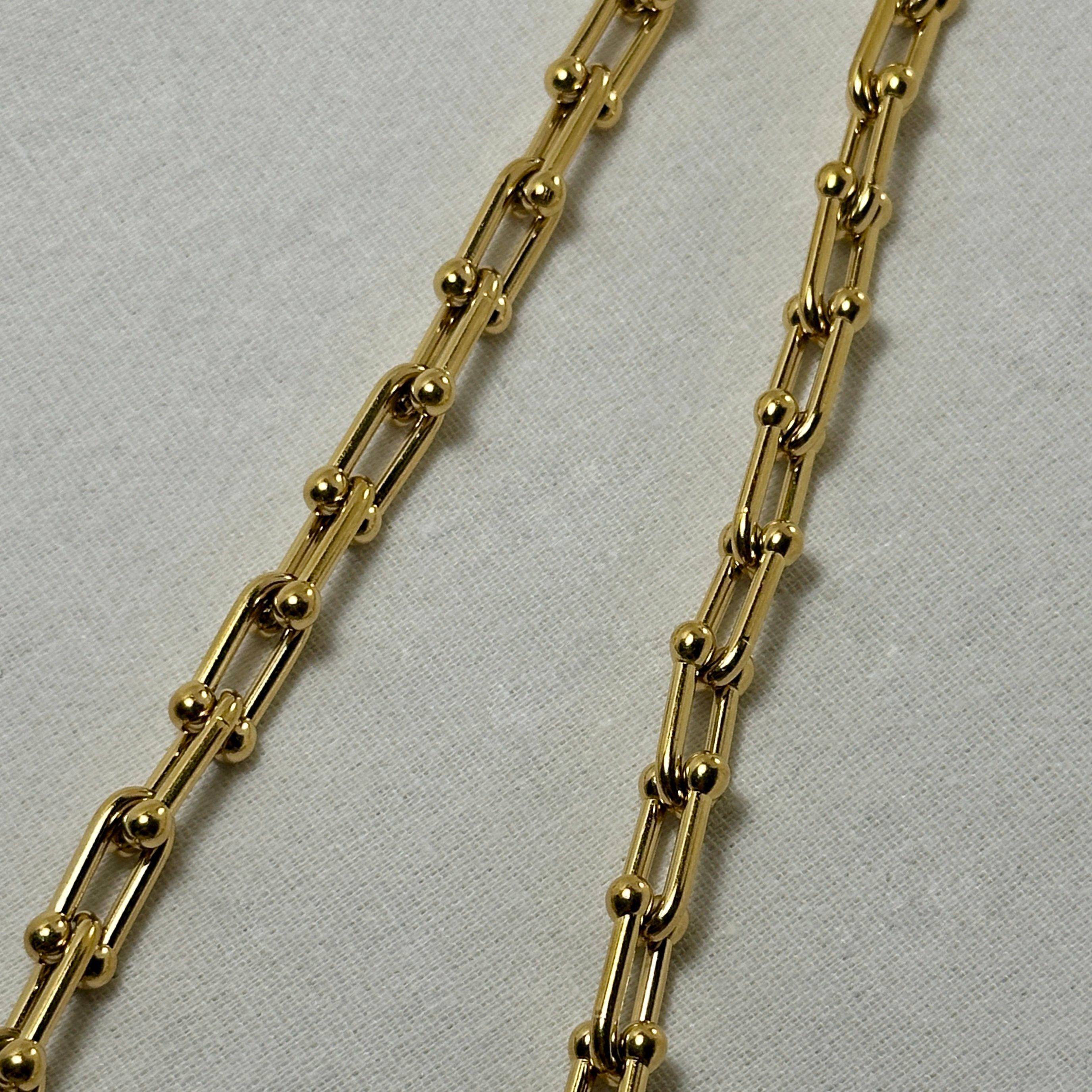 Two gold chain necklaces on white fabric.
