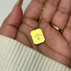 Hand holding gold pendant necklace with engraved text I AM STRONG and small symbol