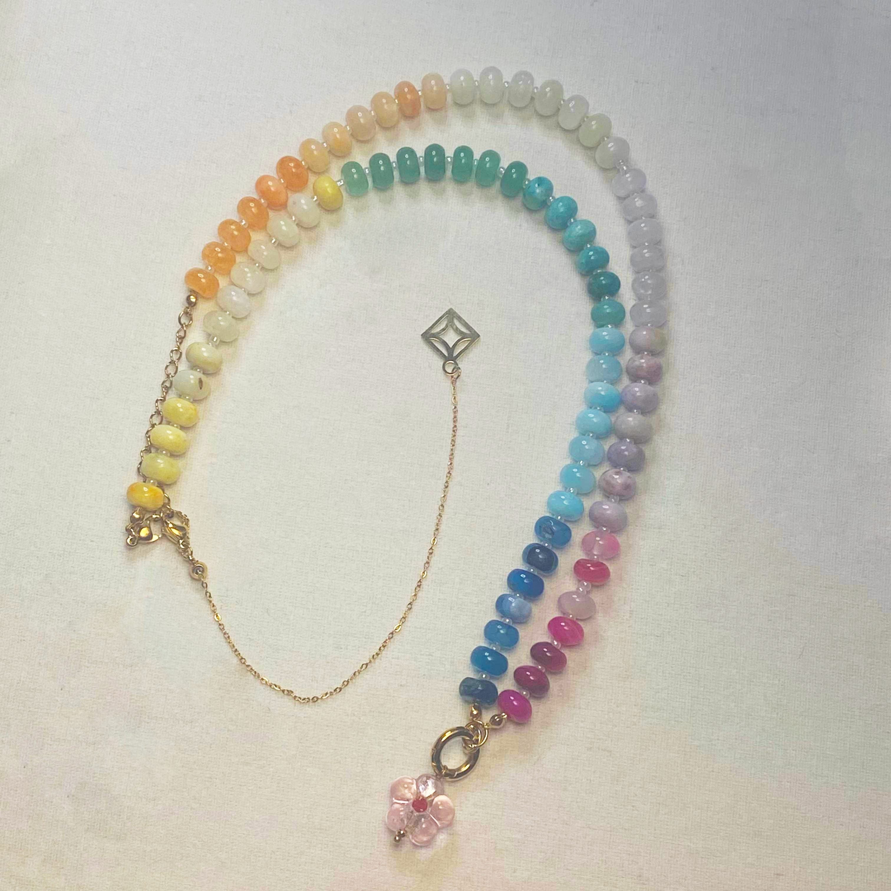 Indra Multicolored beaded gold necklace chain with a pink crystal pendant on a white  background and lumenaura jewellery 