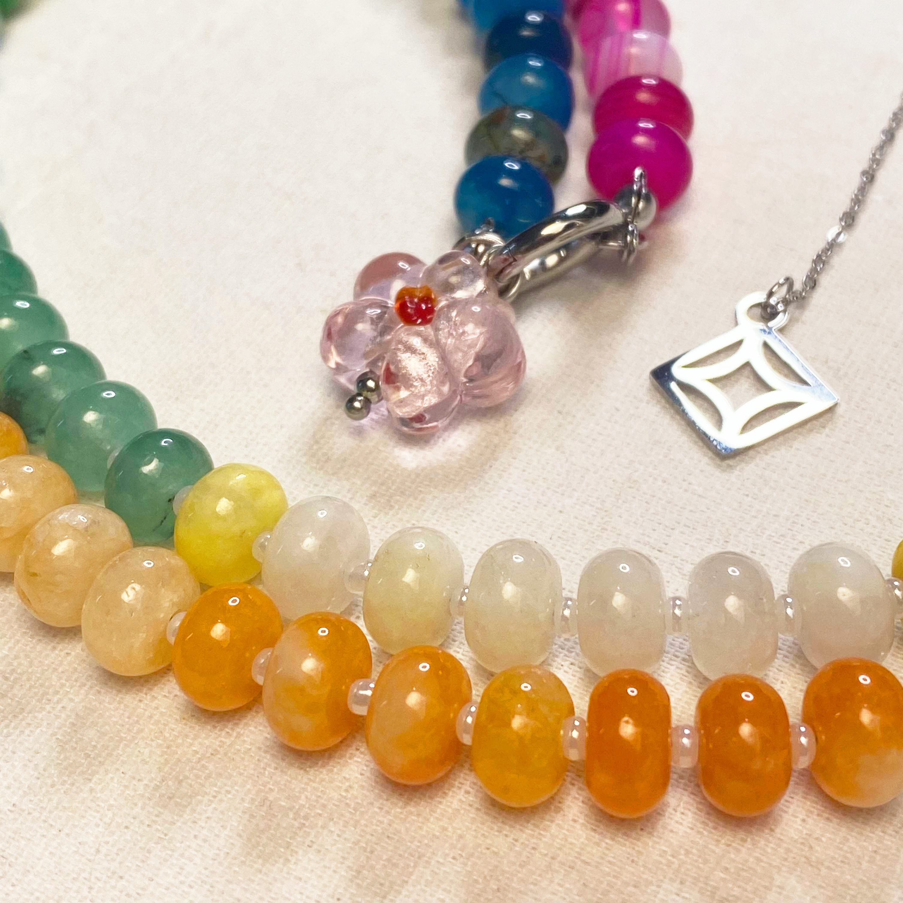 Indra Colorful beaded necklaces with silver pendants on a beige surface and lumenaura jewellery 