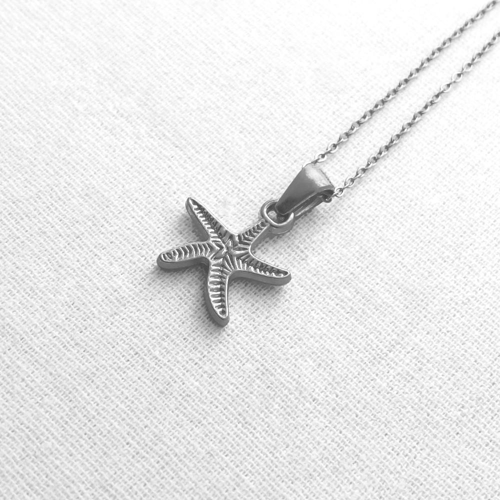 Silver starfish pendant on a chain against a light gray background