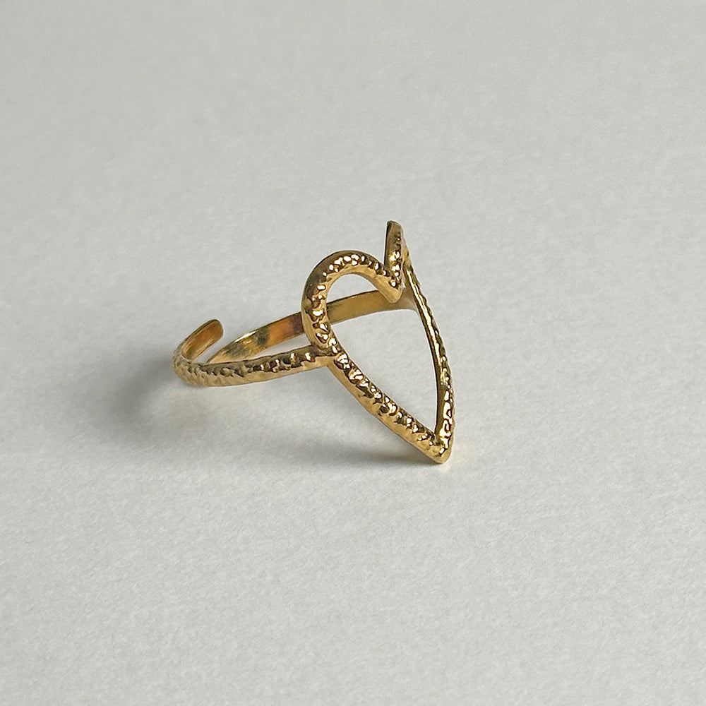 A gold open heart-shaped ring with a textured, hammered finish on a light gray background.