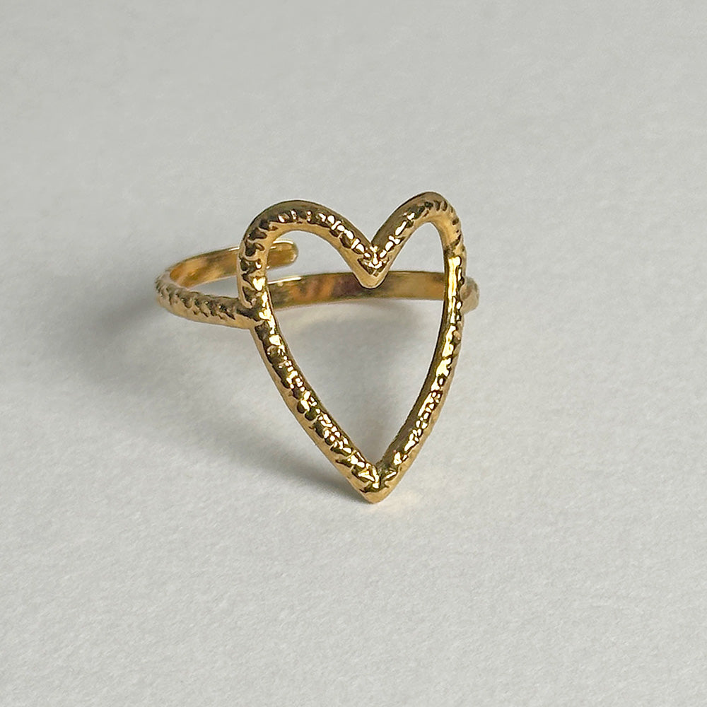 A gold heart-shaped ring with a textured, hammered finish on a light gray background.
