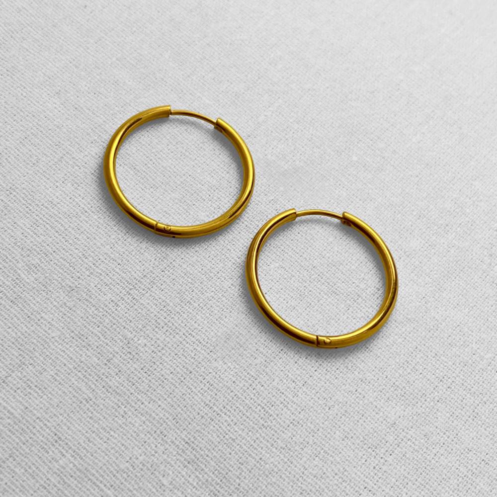 Gold hoop earrings on a light gray textured background