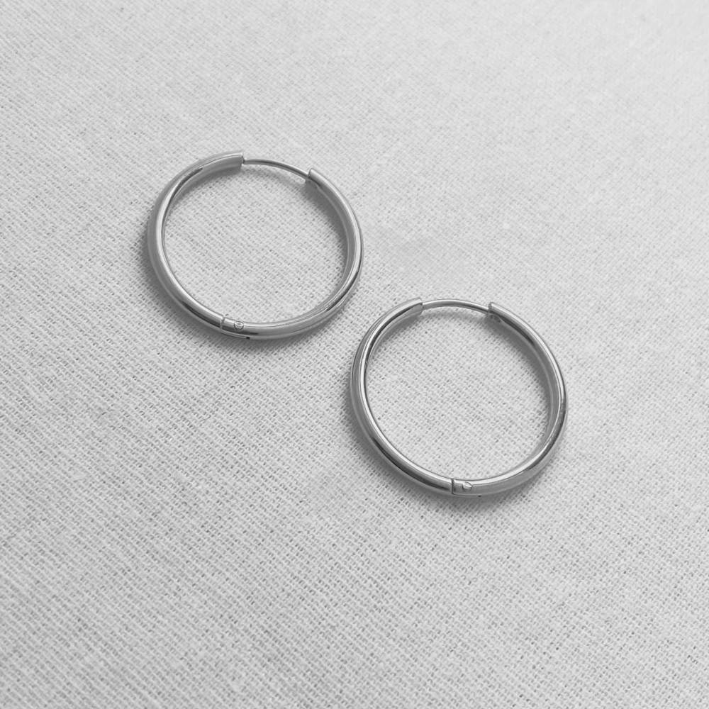 Pair of silver hoop earrings on a light gray textured background