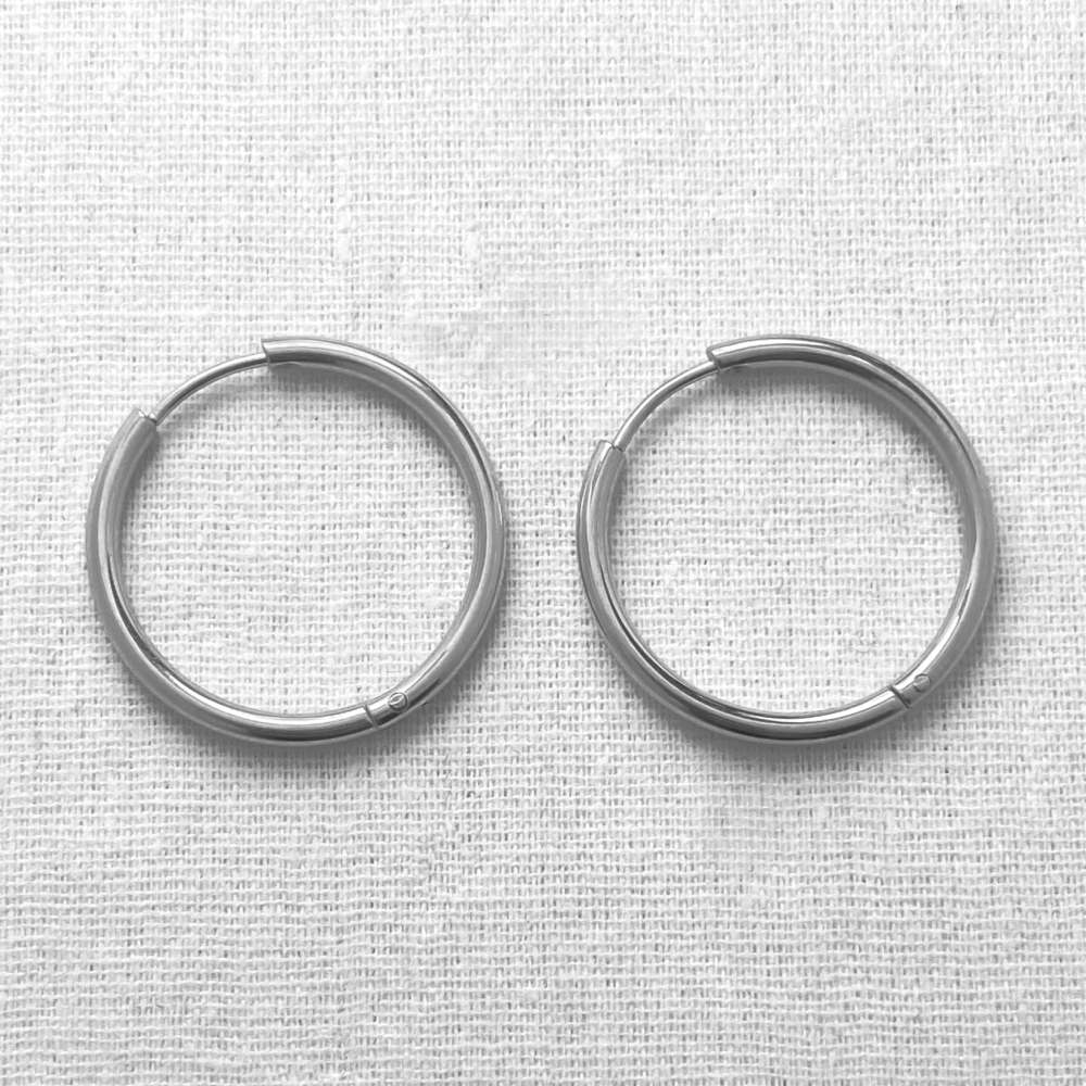 Two silver hoop earrings on a textured white background