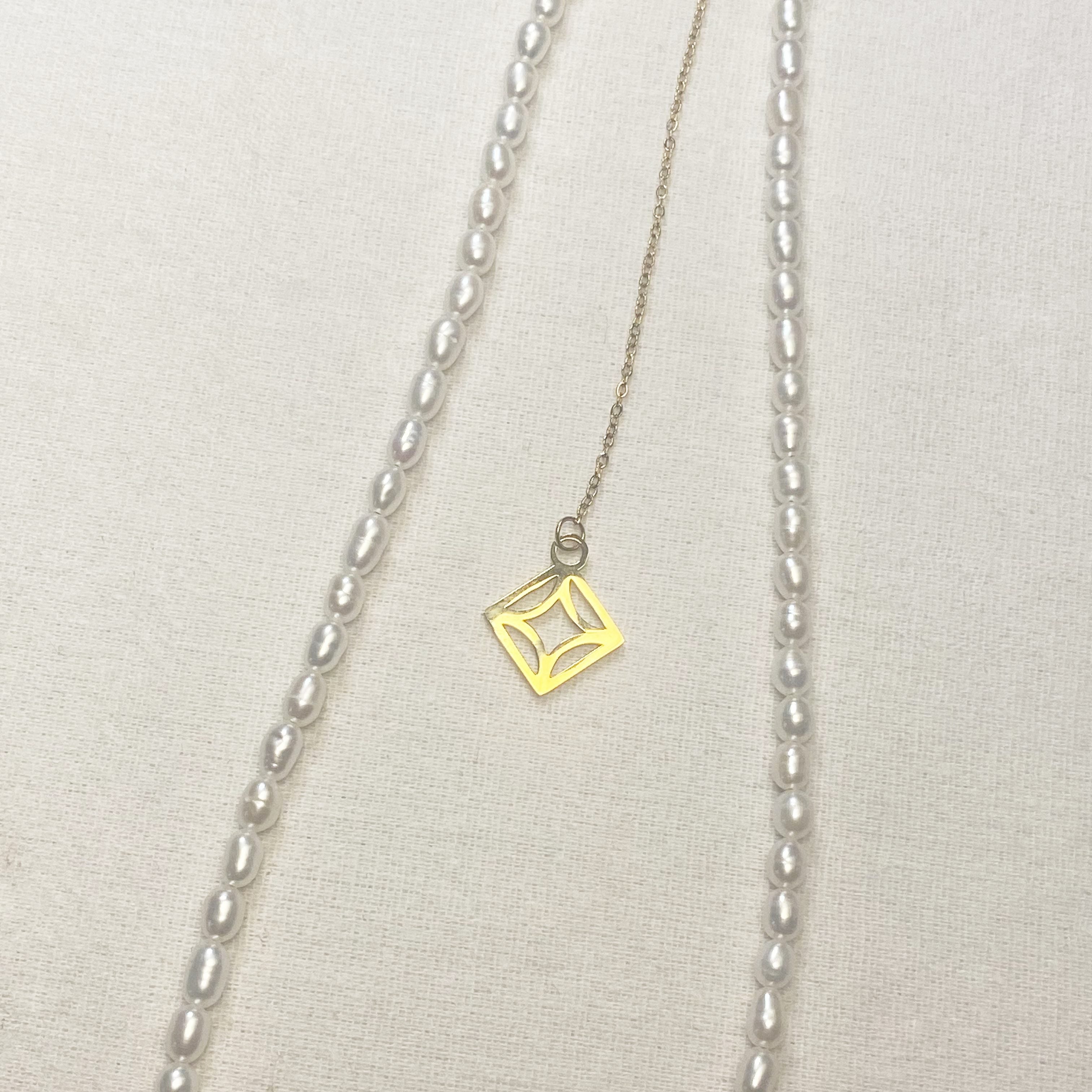 Necklace with a gold square pendant on a light gray background and lumenaura jewellery 