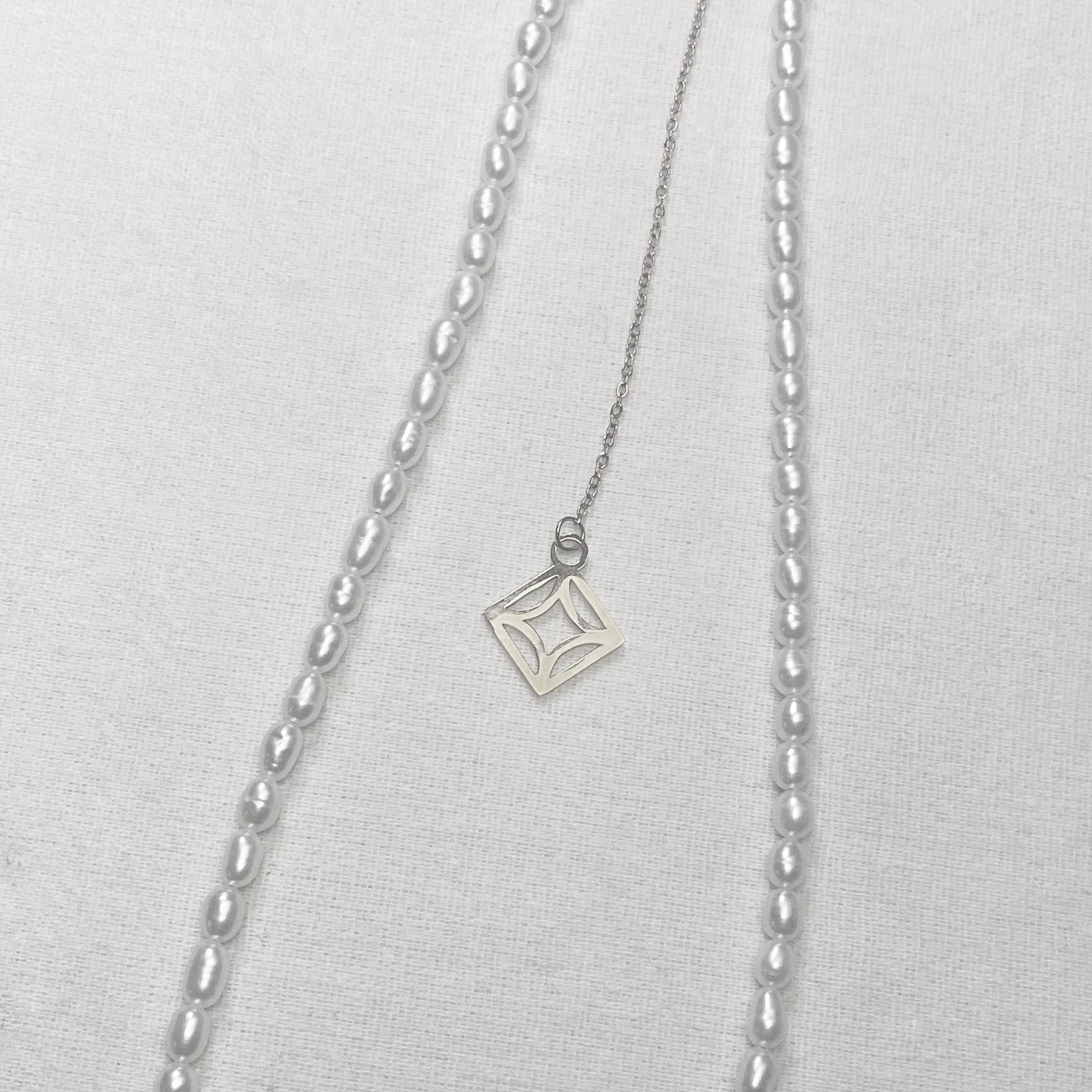 Silver necklace with a square pendant on a light gray background and lumenaura jewellery 