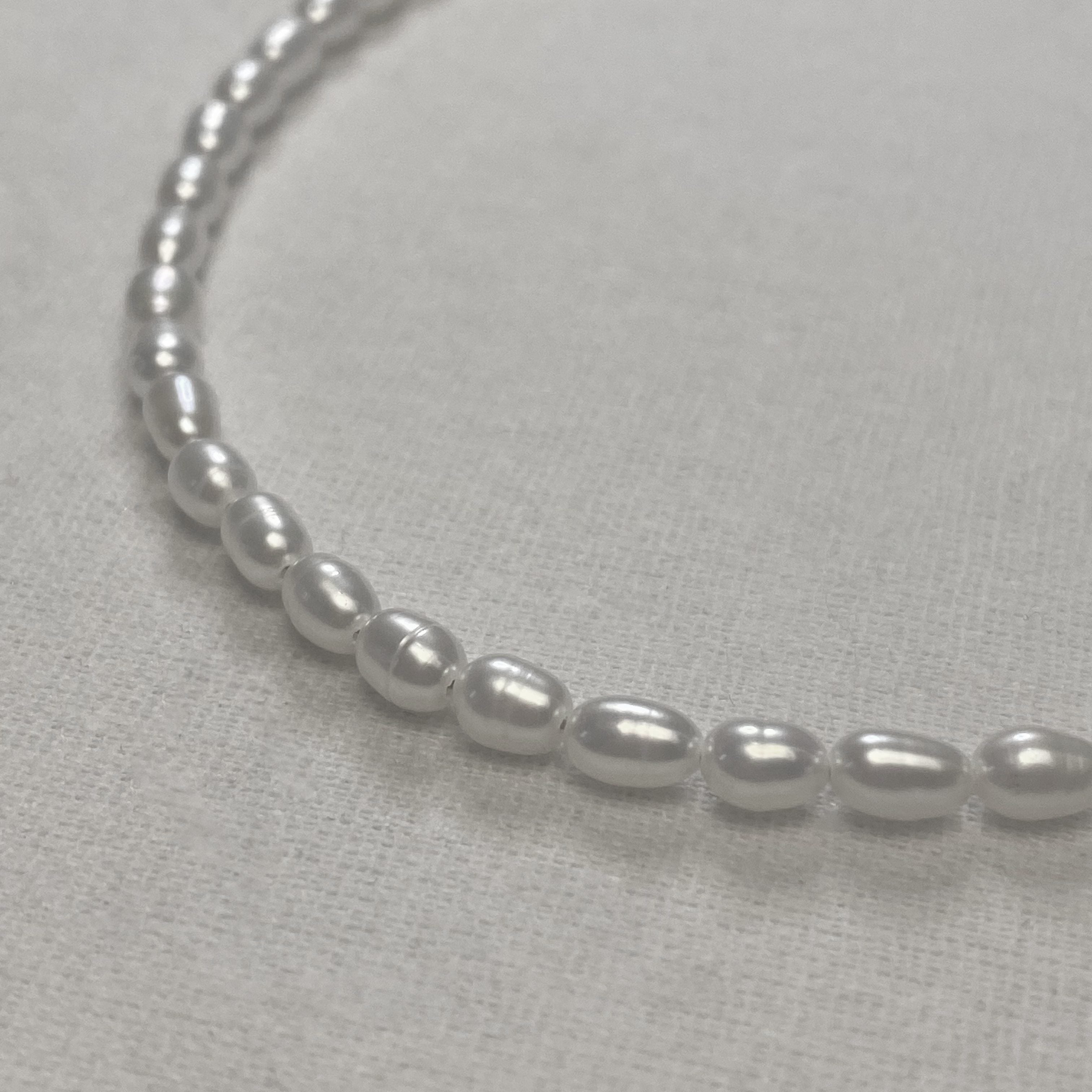 Pearl necklace on a light gray background and lumenaura jewellery 