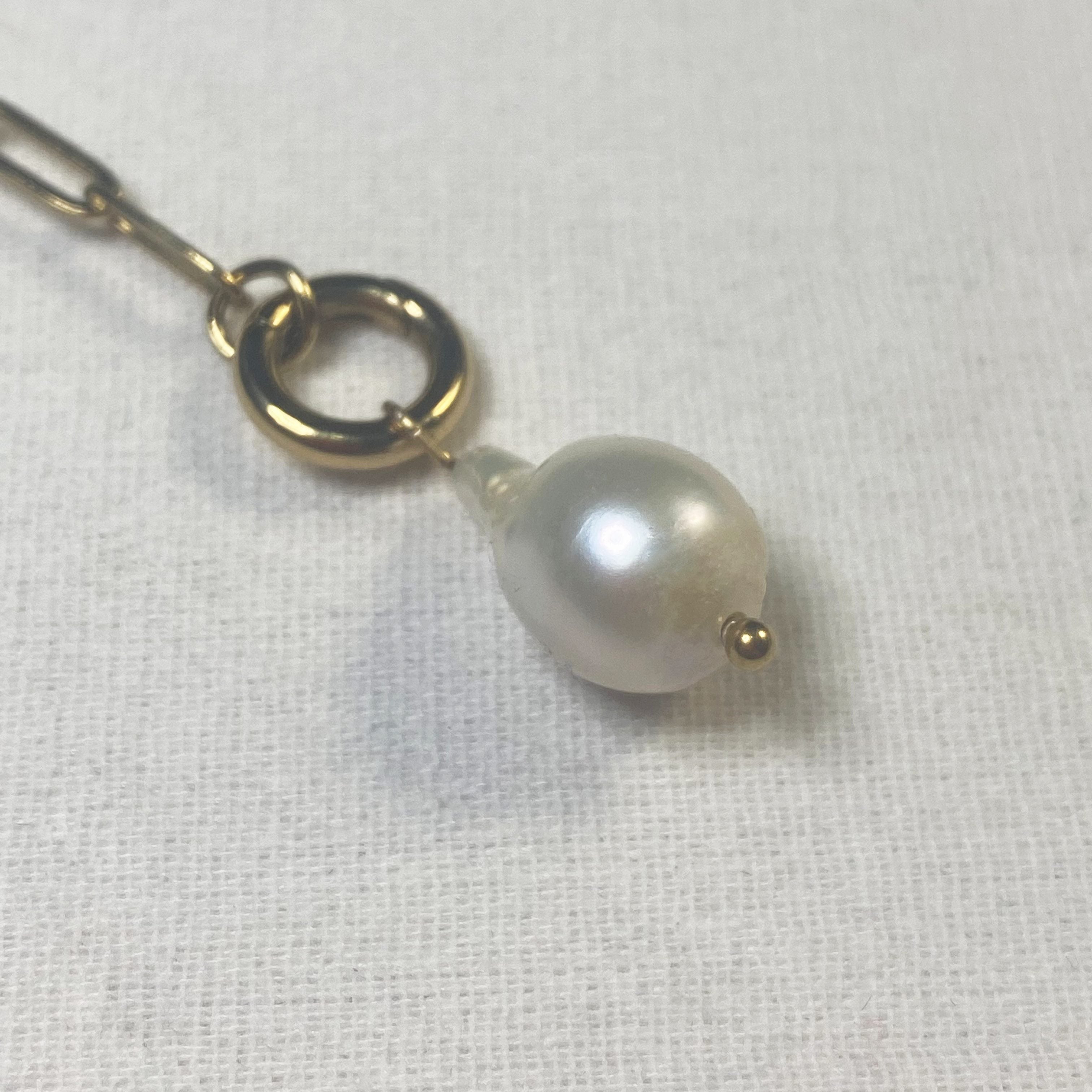 Pearl hairpin with gold clip on a white fabric background and lumenaura jewellery 