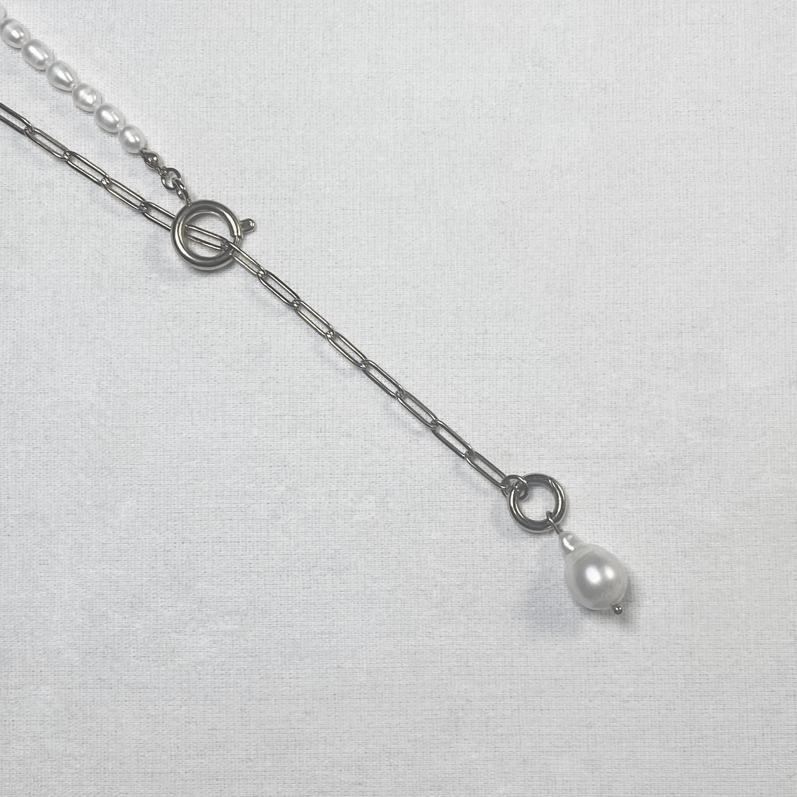 Pearl necklace with silver chain on a light gray background and lumenaura jewellery 