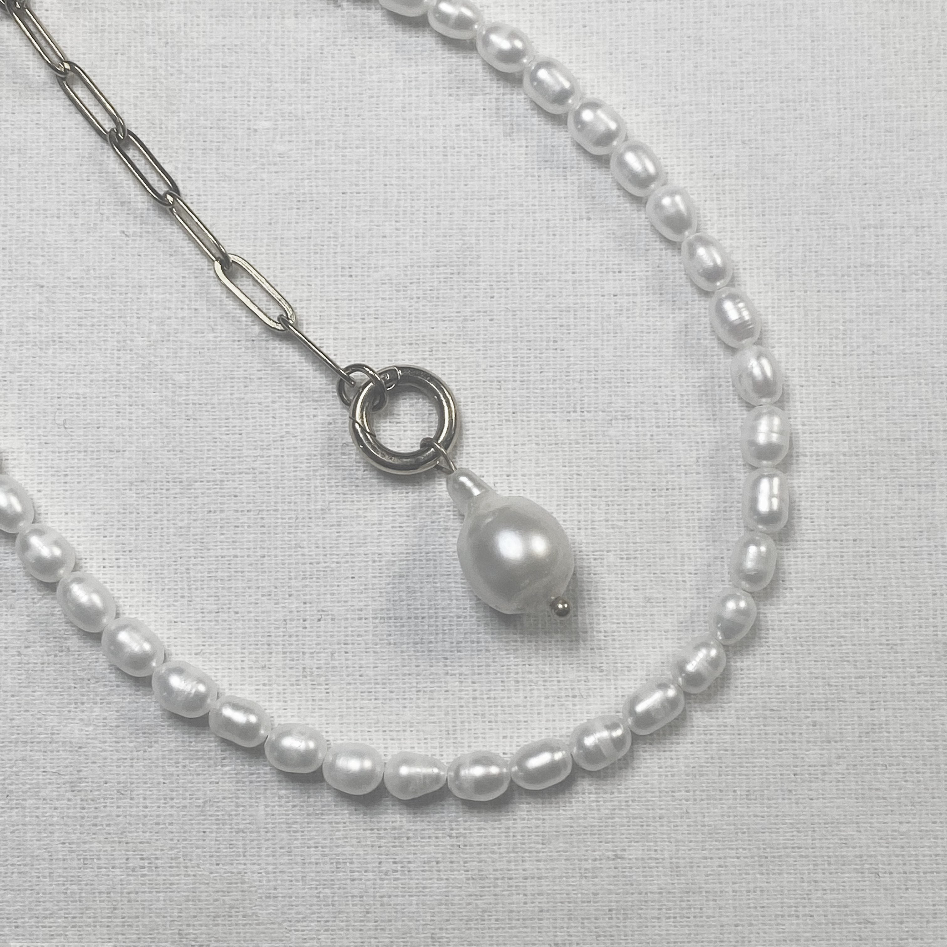 Pearl necklace with a silver chain and pendant on a light gray background and lumenaura jewellery 