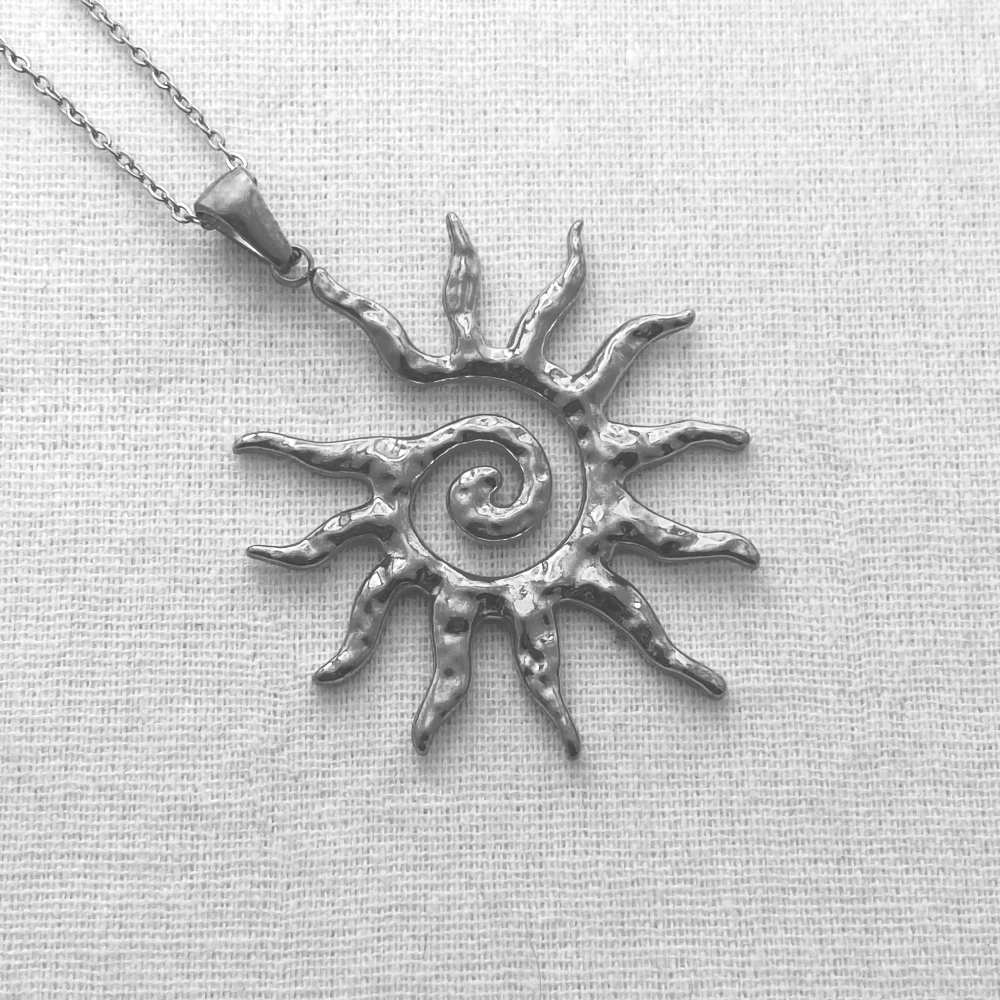 Silver sun-shaped pendant on a chain against a light gray background