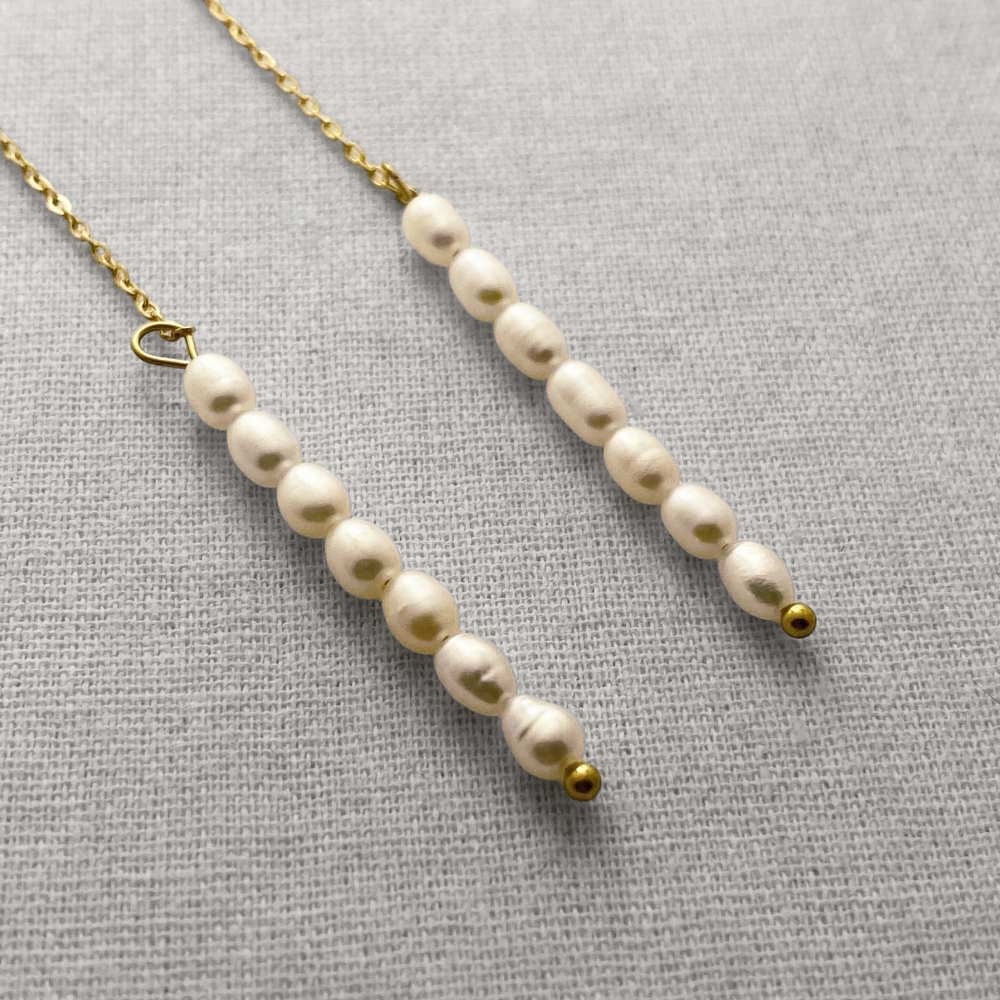 Pearl necklace with gold clasps on a beige fabric background