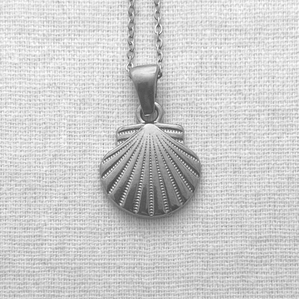 Silver shell pendant necklace on a light gray fabric background