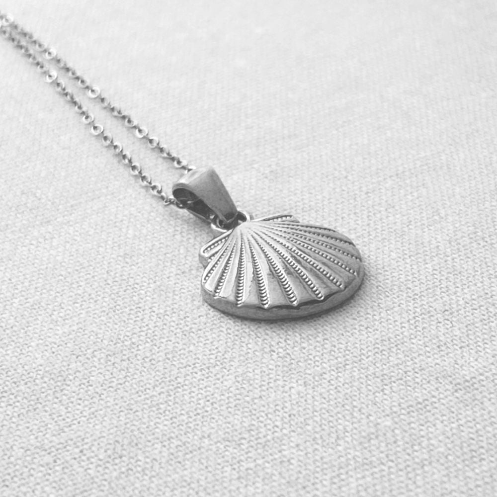 Silver shell pendant necklace on a light gray background